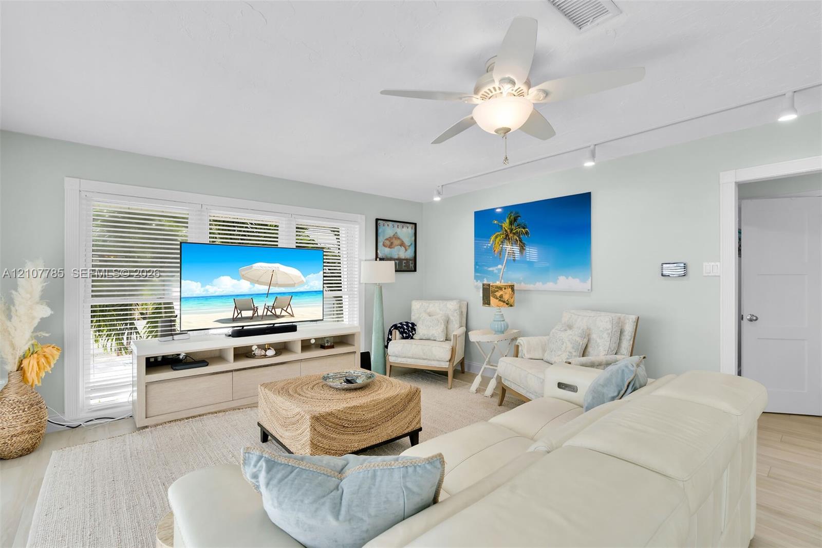 Living area featuring light-toned wood-finish flooring, recessed track lighting, a ceiling fan with integrated light fixture, and windows equipped with horizontal blinds