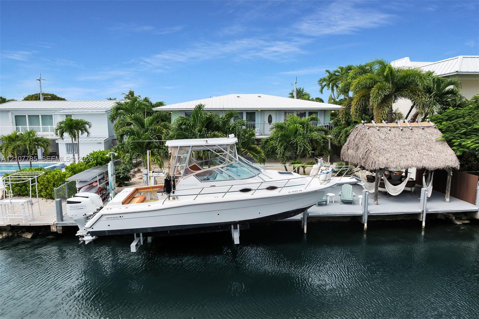 Private dock featuring a built-in thatched-roof gazebo, concrete sea wall, and direct canal access