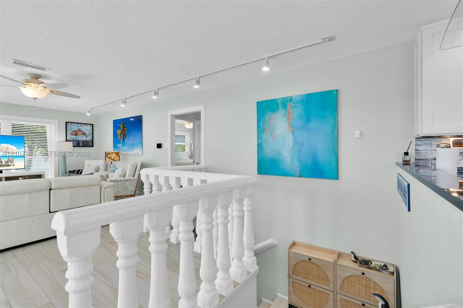 White balustrade railing, track lighting, ceiling fan with integrated light fixture, and light-toned tile flooring
