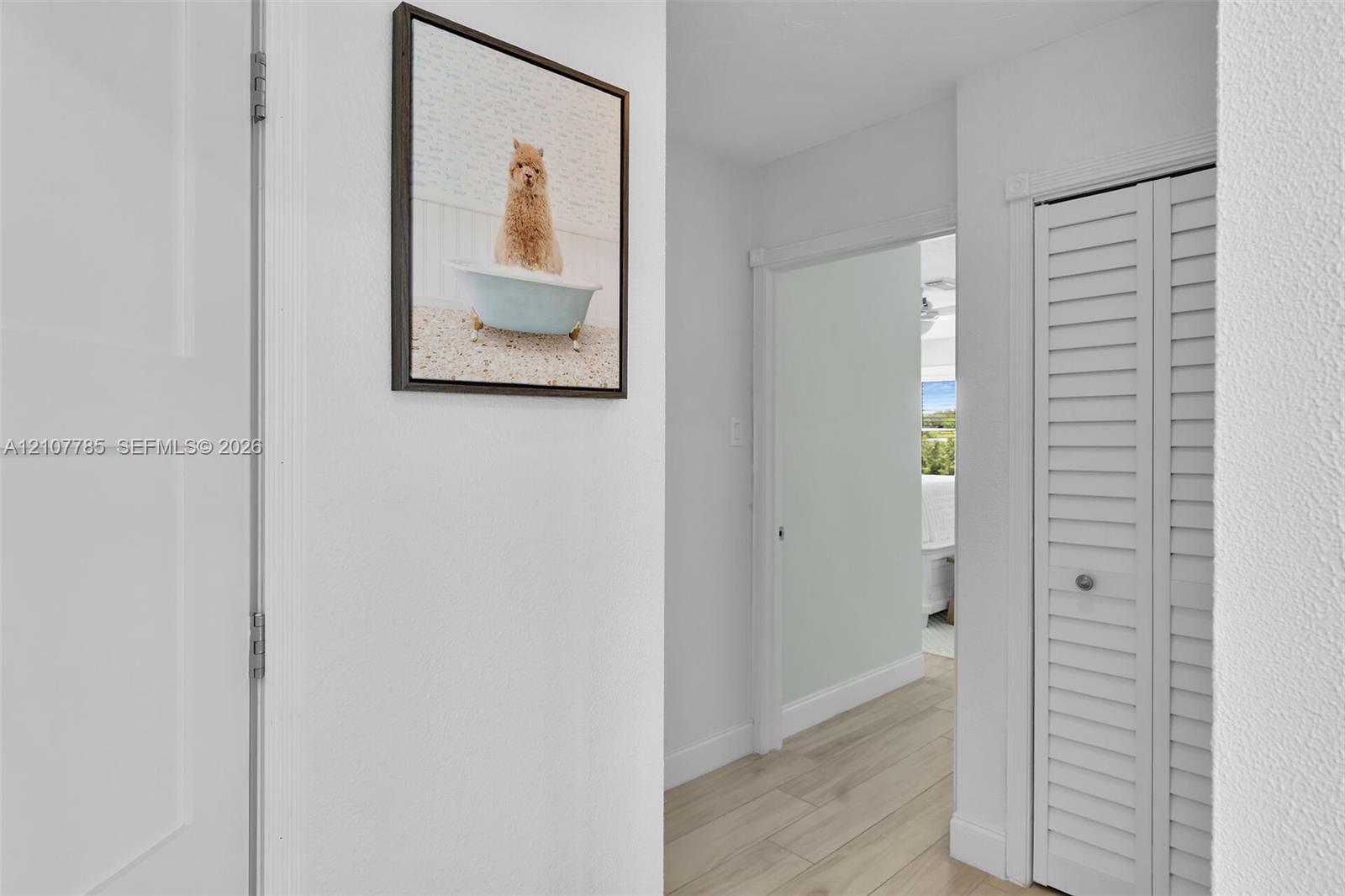 Hallway featuring wood-finish flooring and a closet with white louvered bi-fold doors