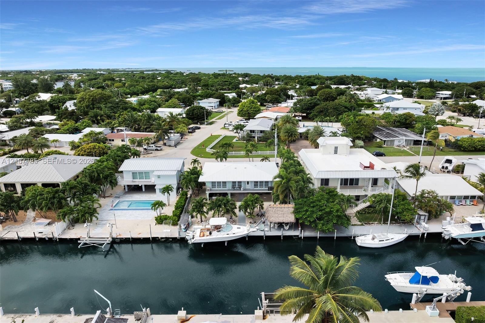 Waterfront residential property featuring a private boat dock, tiki-style structure, and metal roof system