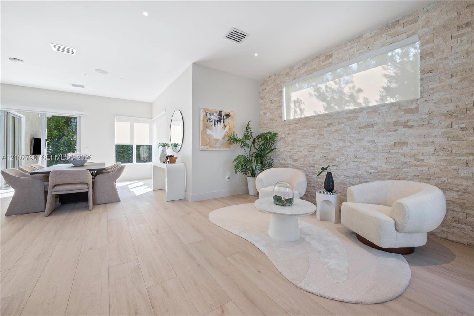Textured stacked-stone accent wall, wide-plank light wood-finish flooring, recessed lighting, and horizontal clerestory window