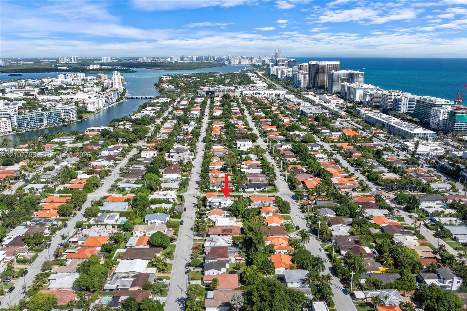 Aerial perspective of a residential lot situated within a coastal urban landscape, featuring proximity to waterfront waterways and high-density commercial districts