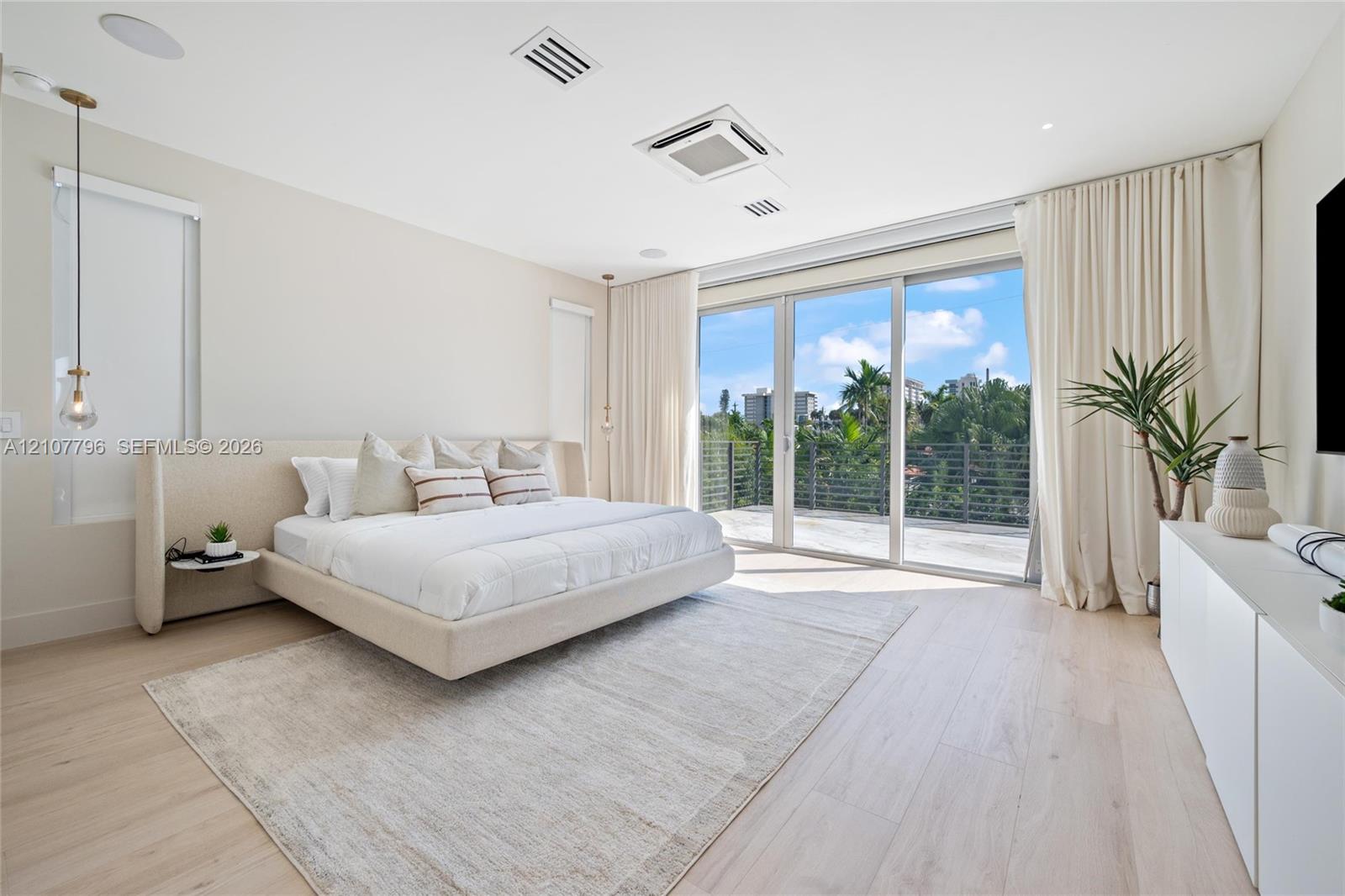 Expansive room featuring wood-finish flooring, recessed ceiling lighting, a built-in sound system, and floor-to-ceiling glass sliding doors opening to an outdoor balcony