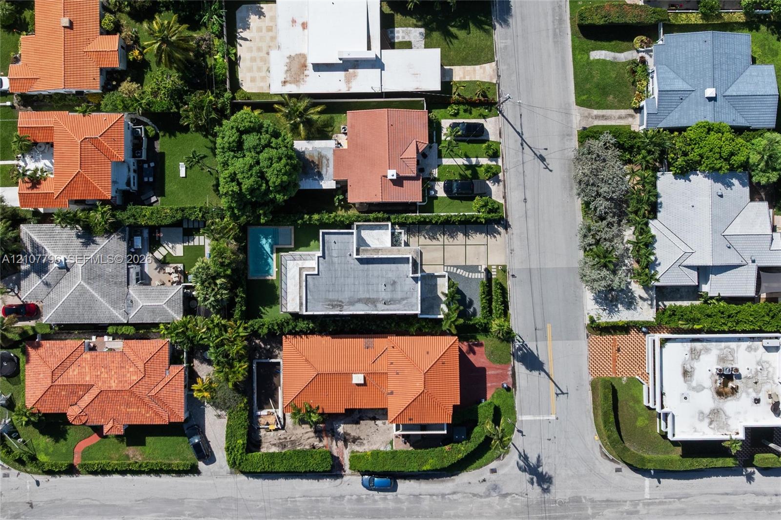 Aerial perspective of the property featuring a private swimming pool, concrete driveway, and mature landscaping