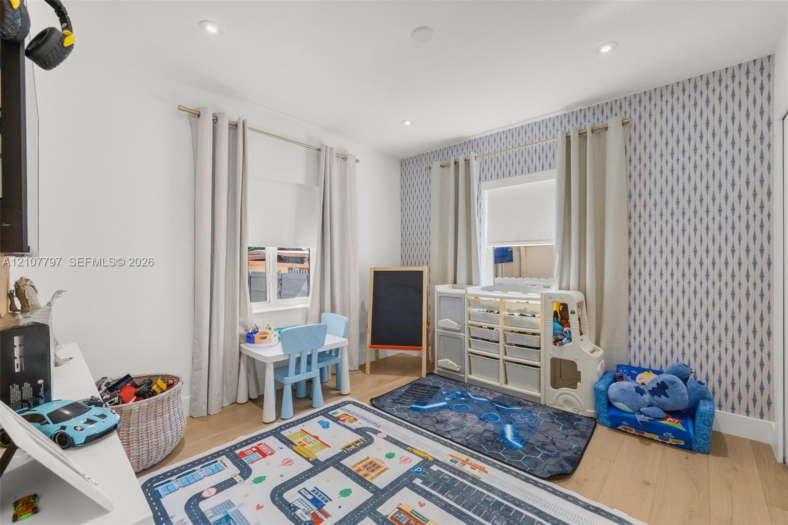 Room featuring wood-finish flooring, recessed lighting, and patterned accent wallpaper