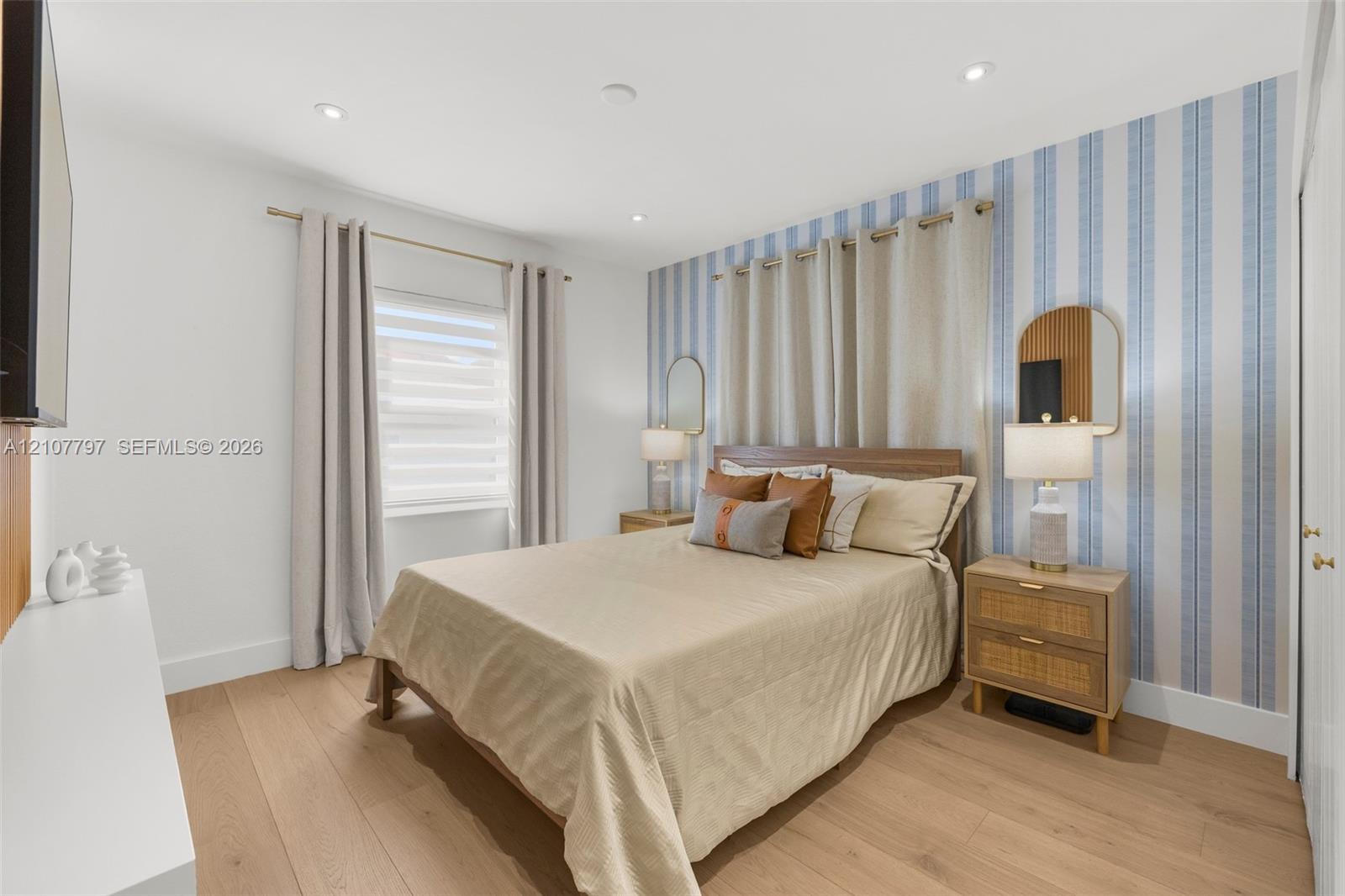 Bedroom featuring wood-finish flooring, recessed lighting, and a blue-and-white striped accent wall with dual wall-mounted mirrors