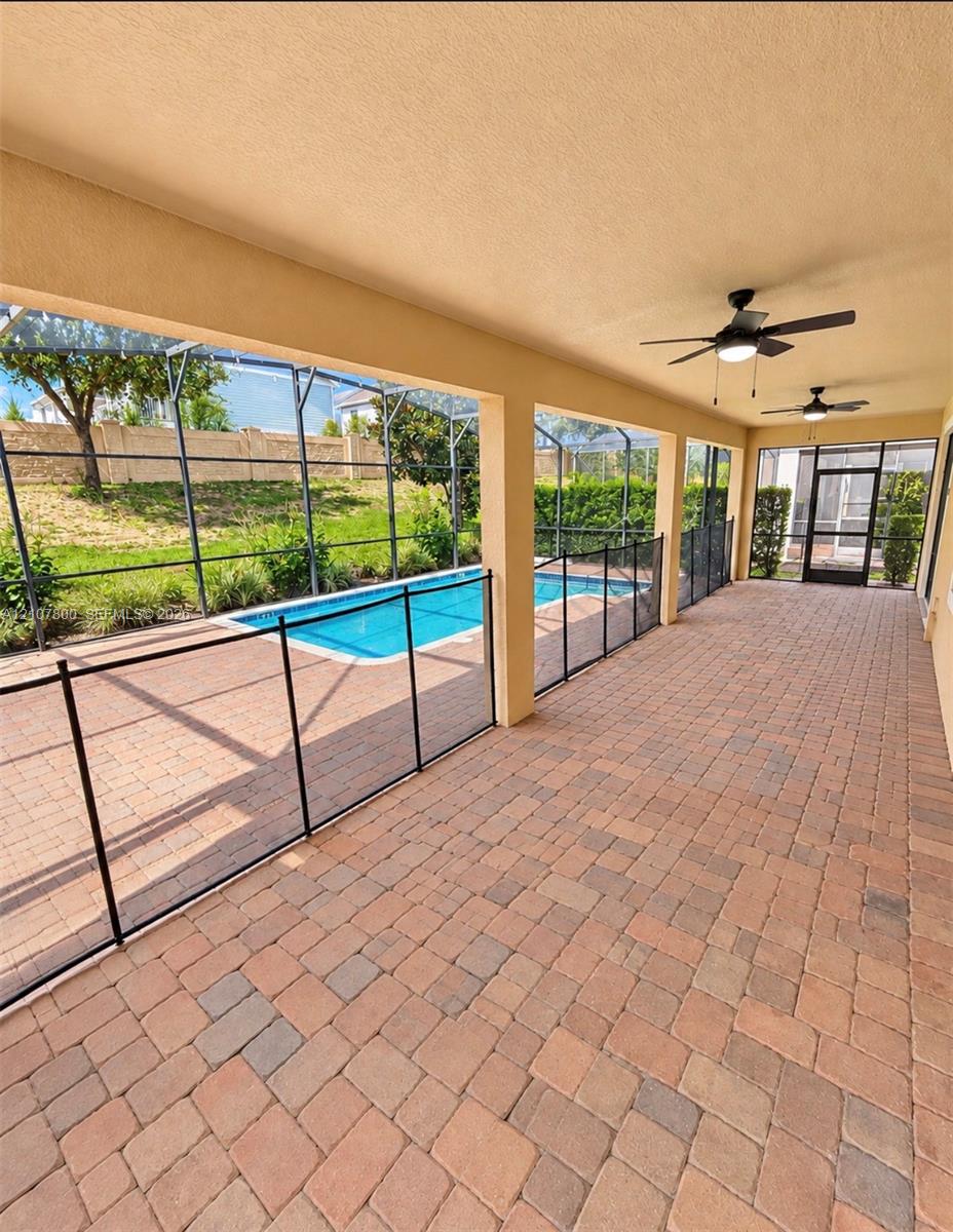 Covered lanai featuring brick paver flooring, recessed ceiling fans, and an enclosed screen structure surrounding an in-ground swimming pool