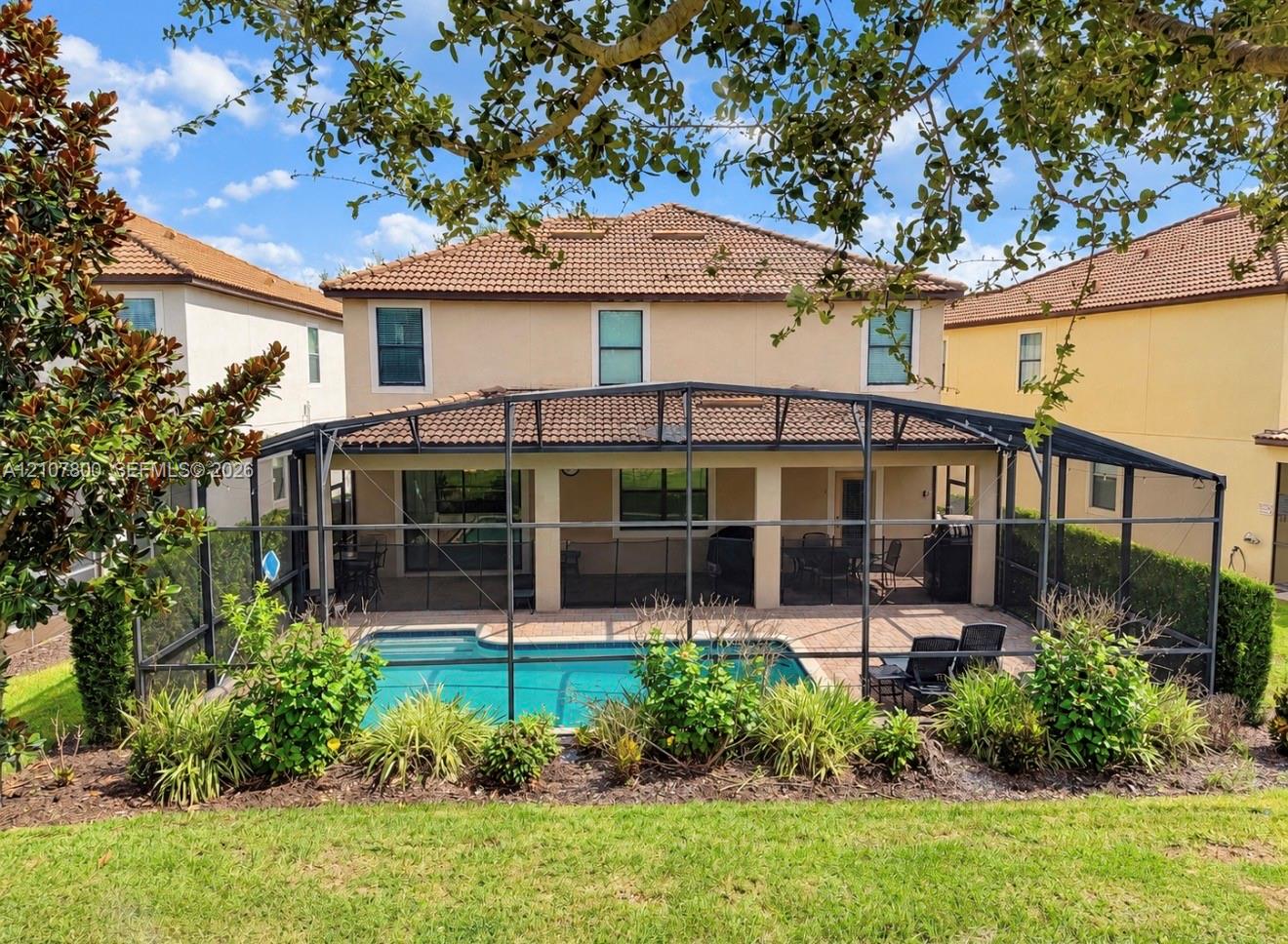 Screen-enclosed patio with a paved deck, private swimming pool, stucco exterior, and multi-pitched tile roof