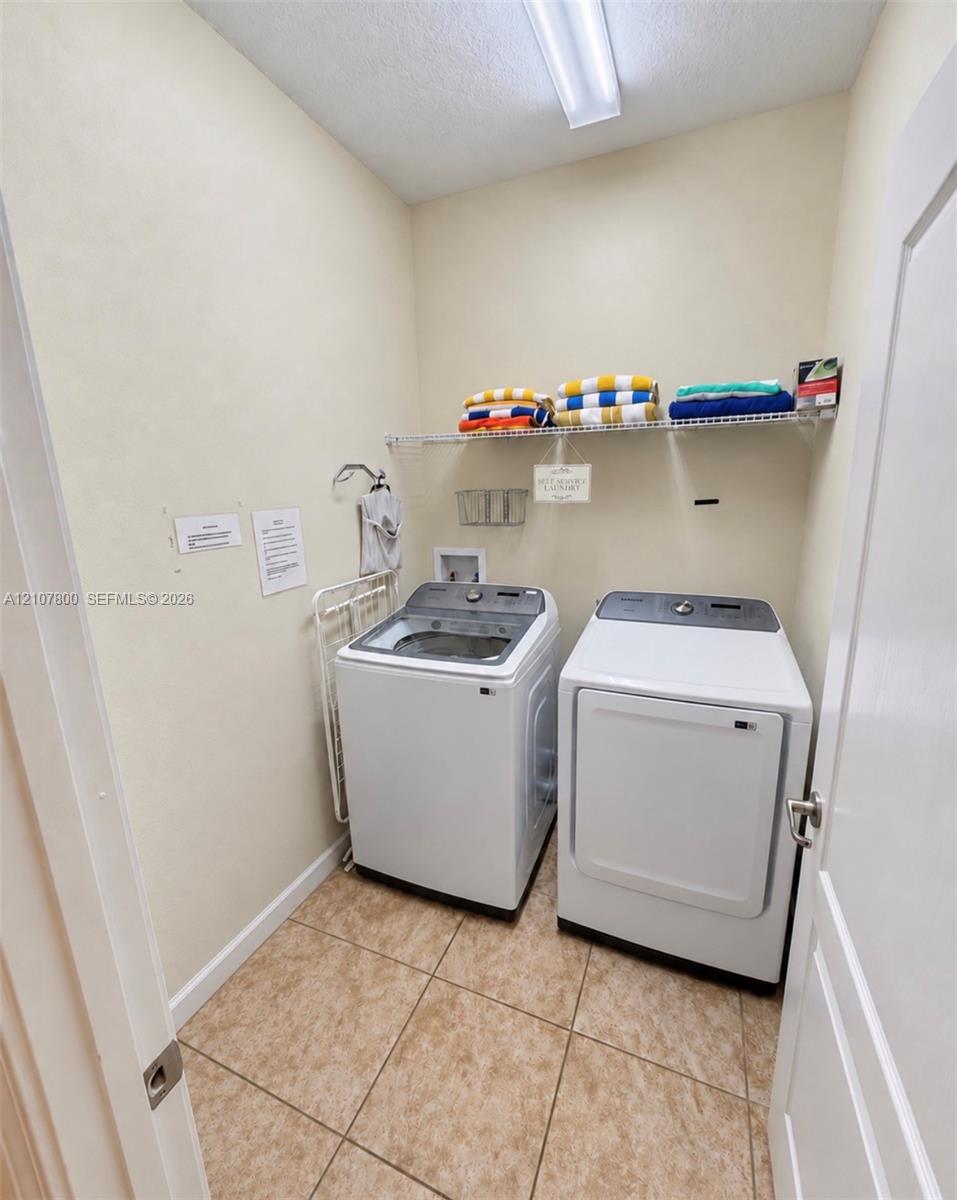 Laundry area featuring tile flooring, wire shelving, and overhead linear lighting