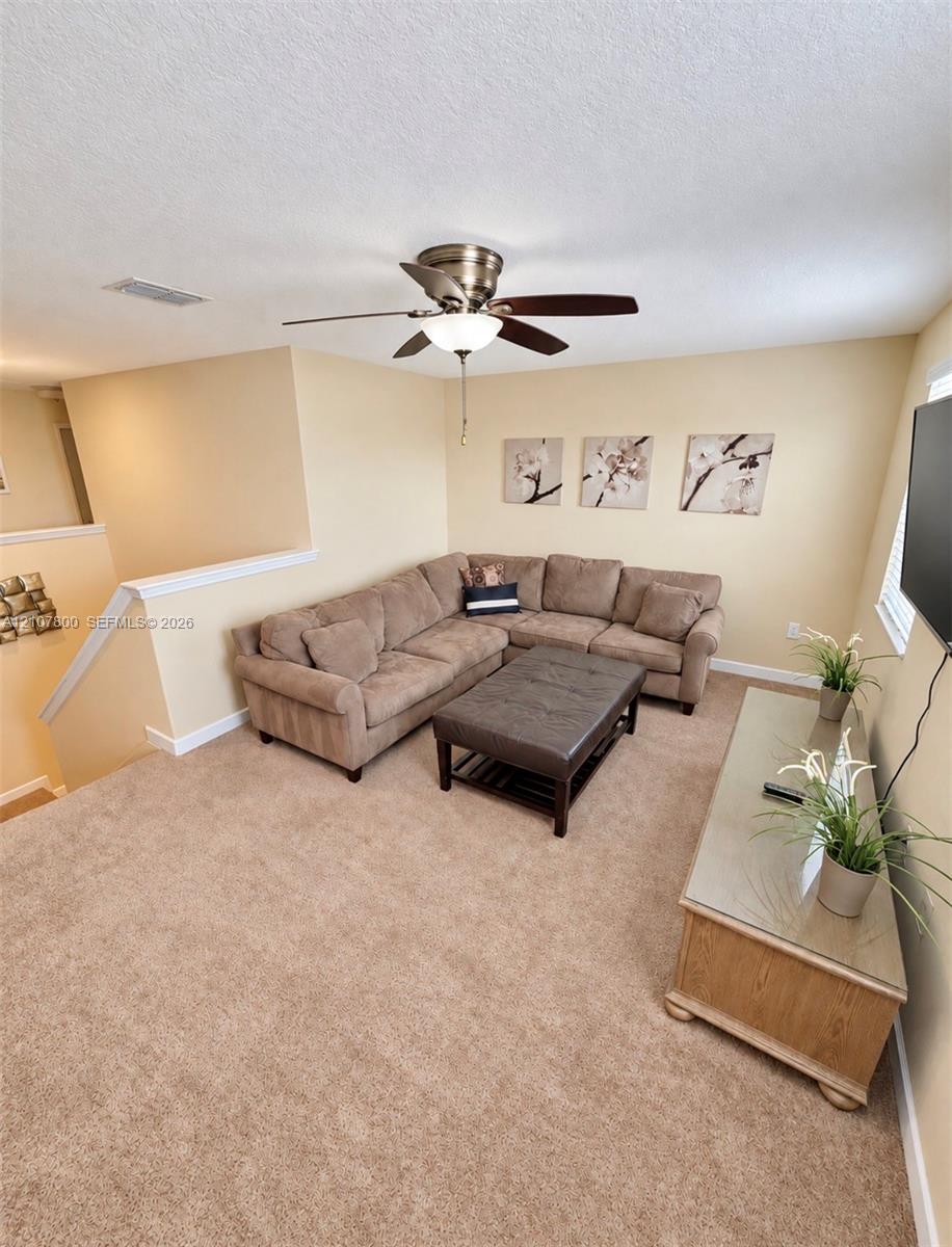 Neutral-toned carpeting and overhead ceiling fan with integrated light fixture