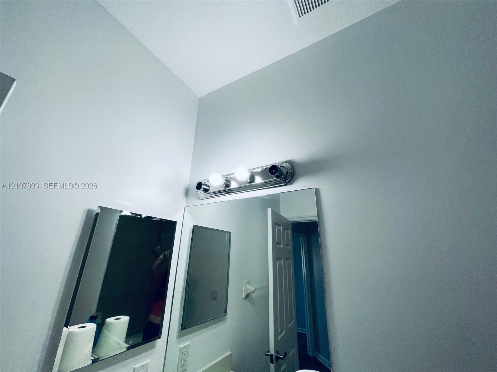 Large frameless mirror accented by a three-light polished chrome vanity fixture