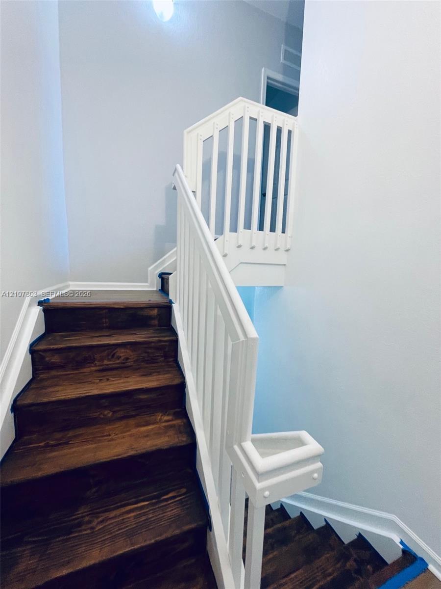 Staircase featuring dark-stained wood treads and white-painted handrails with vertical balusters