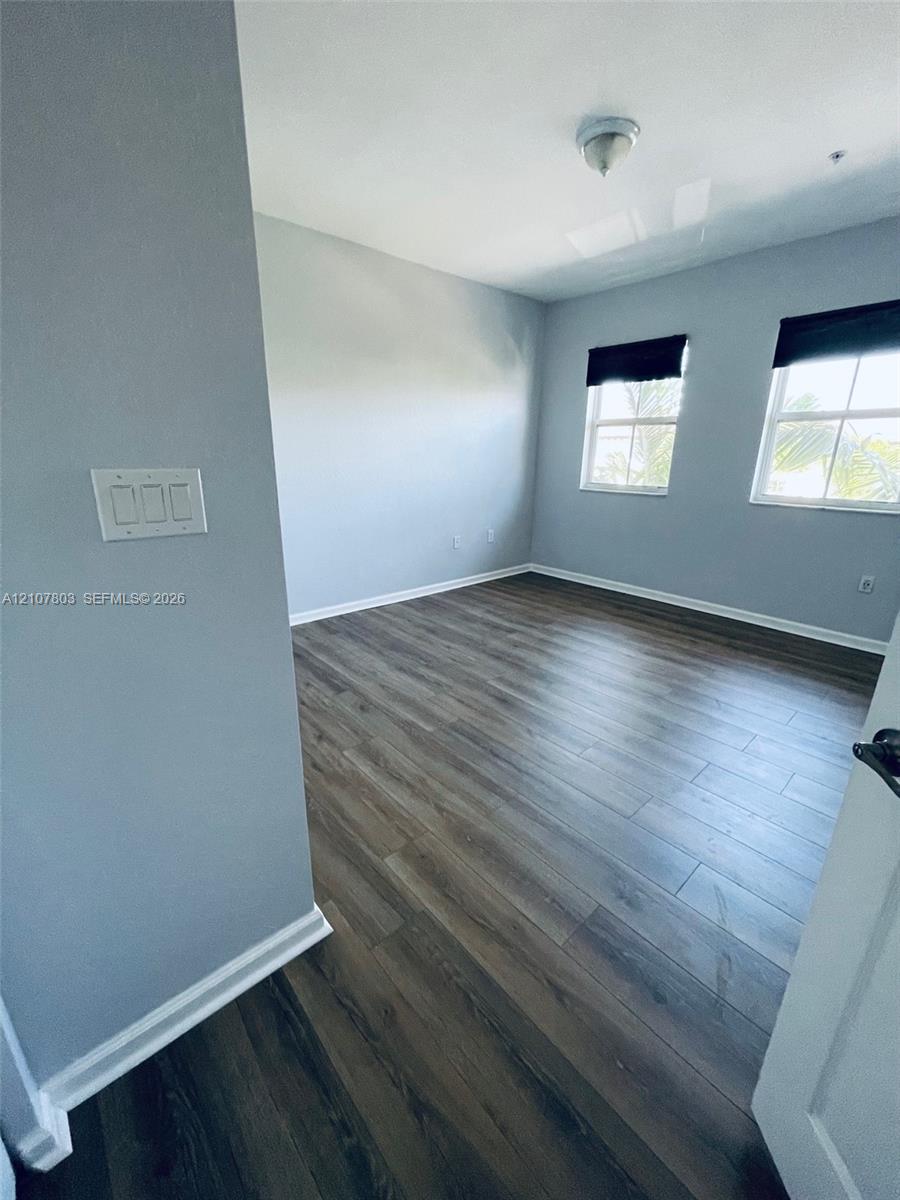 Room featuring wood-finish flooring, dual windows with multi-pane glazing, and neutral wall paint