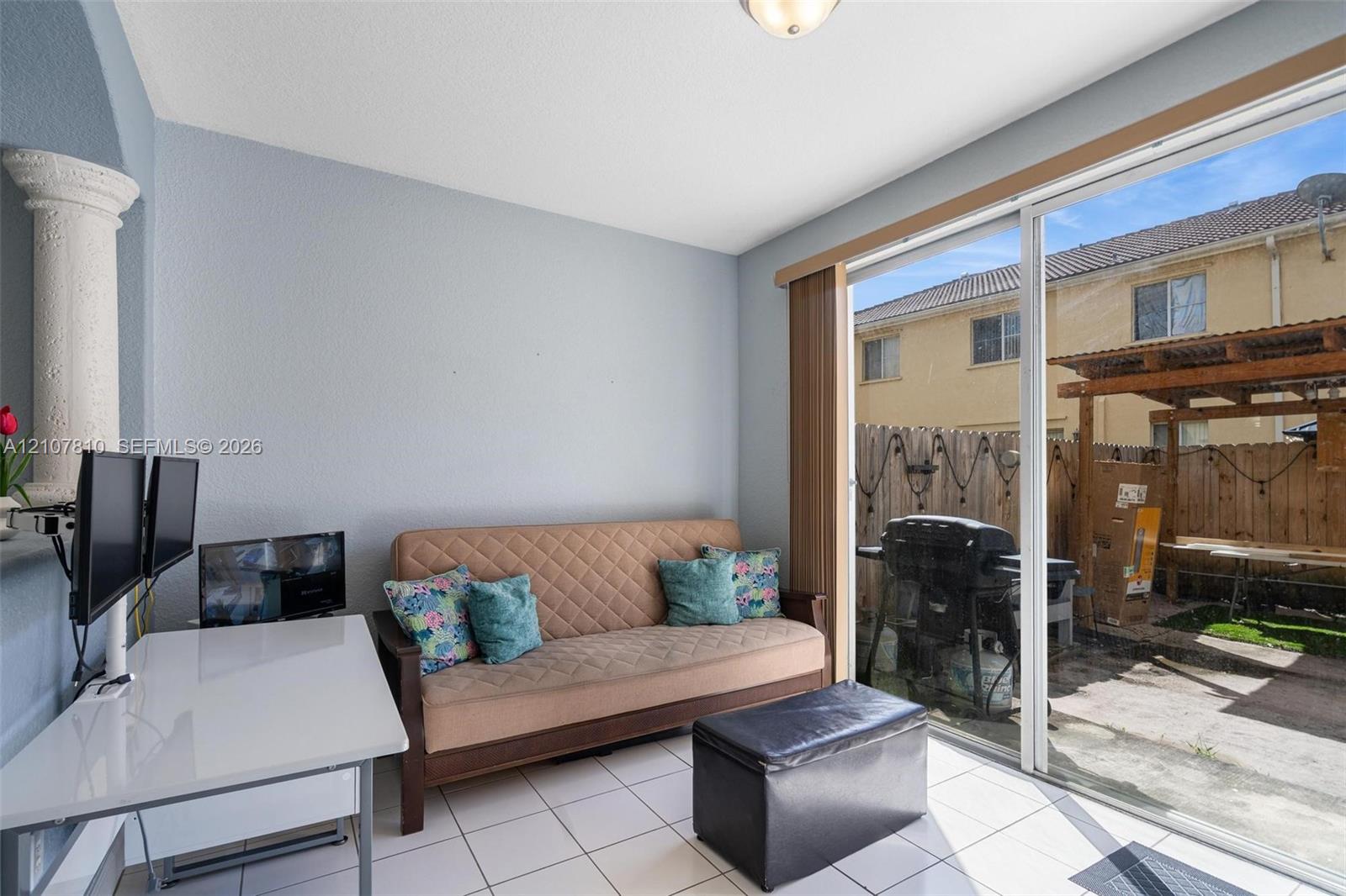 Interior space featuring light-colored tile flooring, a decorative pillar, and a sliding glass door providing access to the exterior