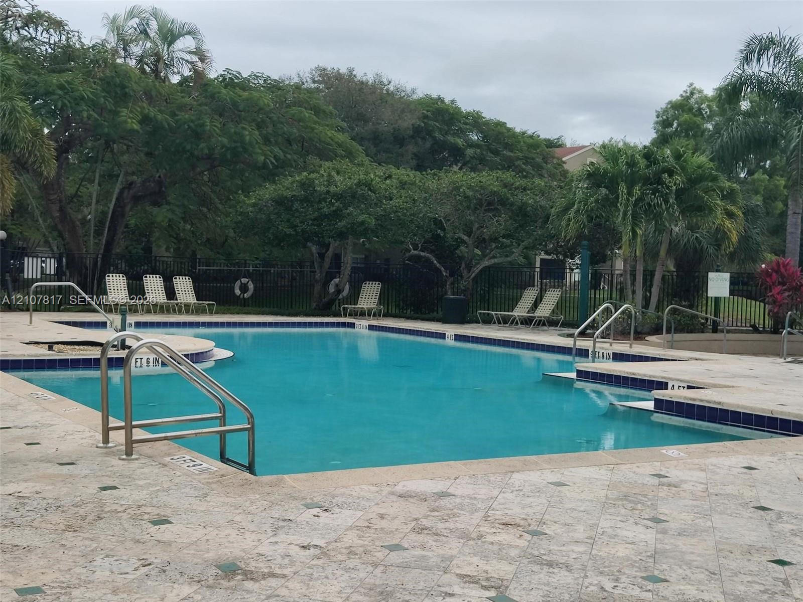 Swimming pool featuring a stone-tile deck, metal entry railings, and integrated steps