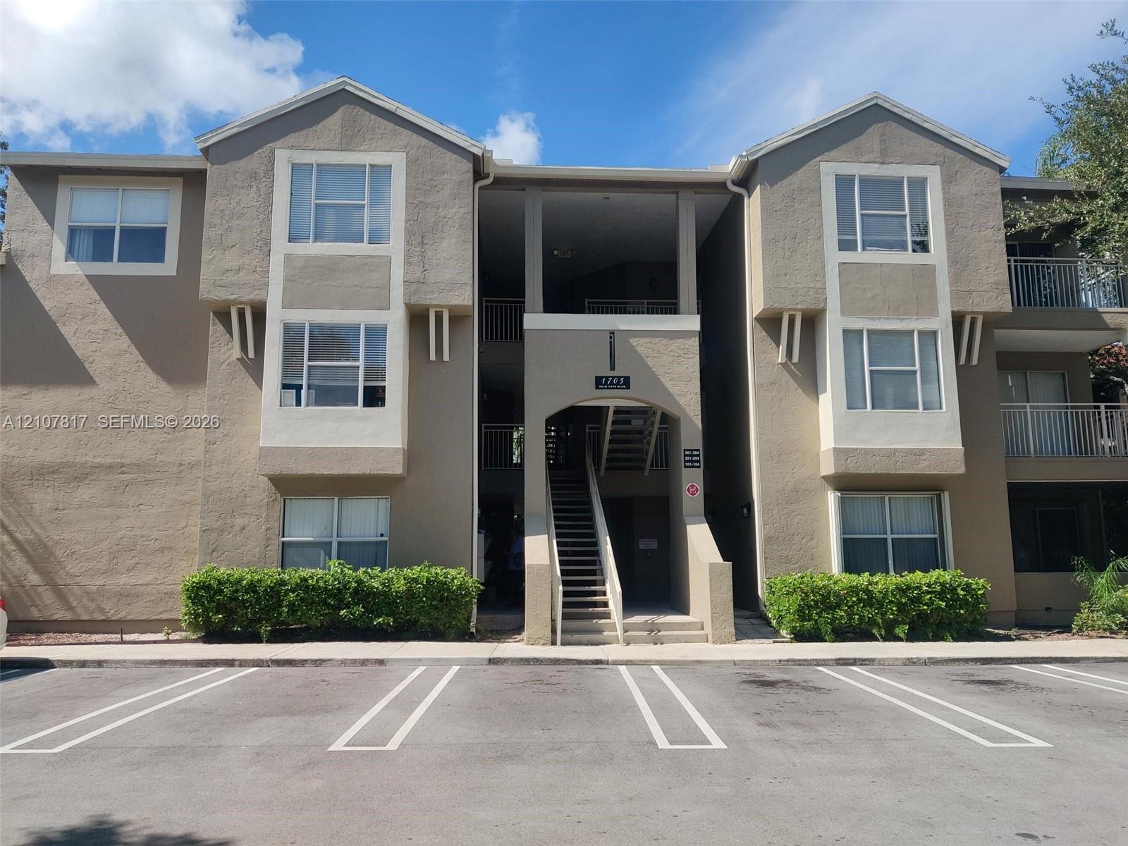 Multi-story stucco exterior featuring projecting bay window profiles, recessed covered stairwell, and manicured foundation landscaping