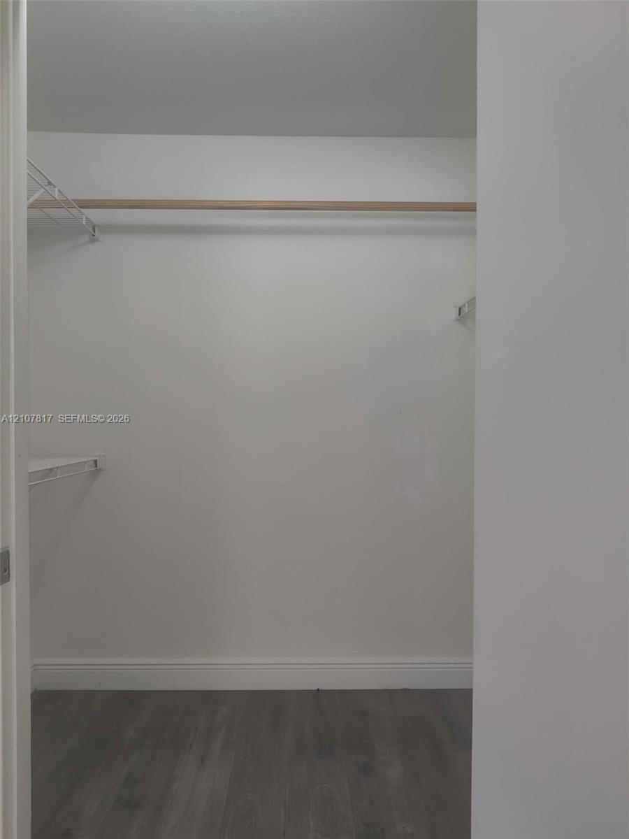 Storage space featuring wood-finish flooring, a full-width hanging rod, and wire shelving