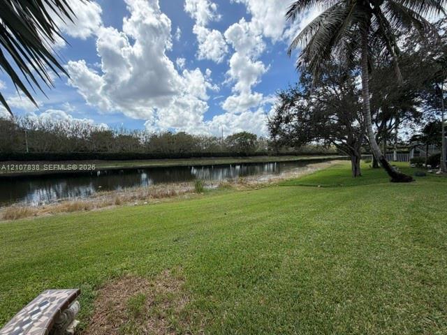 Waterfront grounds featuring a manicured lawn, mature palm trees, and canal frontage
