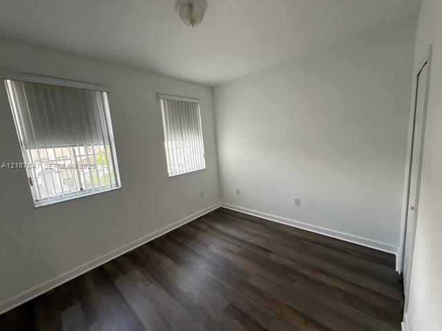 Neutral interior walls with wood-finish flooring, dual windows with vertical blinds, and a built-in closet with sliding doors