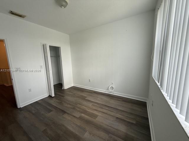Interior space featuring wood-finish flooring, white walls, vertical blinds, and a bi-fold door closet