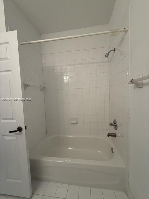 Bathtub and shower combination featuring a white tile surround, integrated soap dish, polished chrome fixtures, and a six-panel door