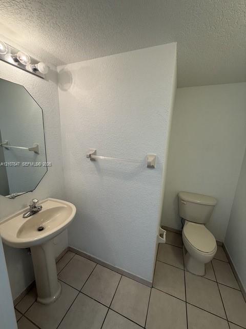 Pedestal sink with single-handle faucet, octagonal mirror, wall-mounted light fixture, and ceramic tile flooring