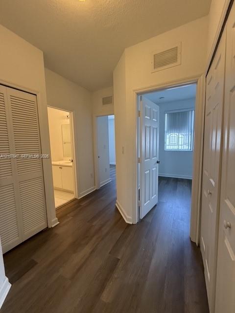 Hallway featuring wood-finish flooring, white paneled doors, and two sets of louvered closet doors