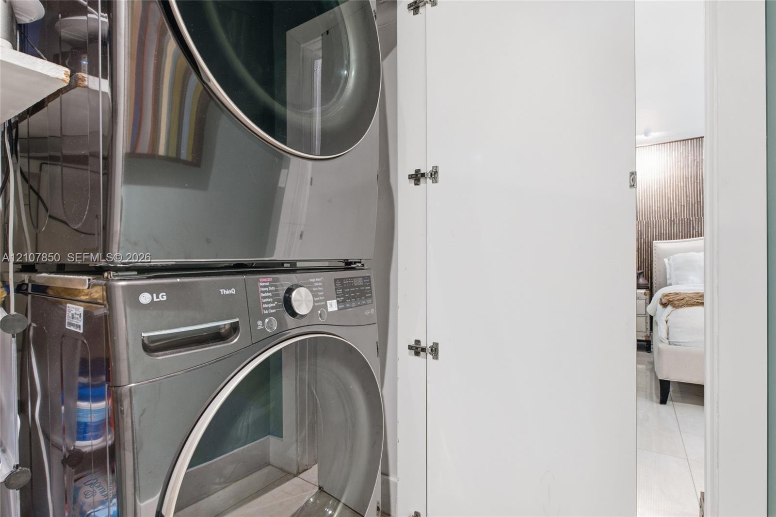 Stacked stainless steel laundry appliances housed within a white cabinetry enclosure