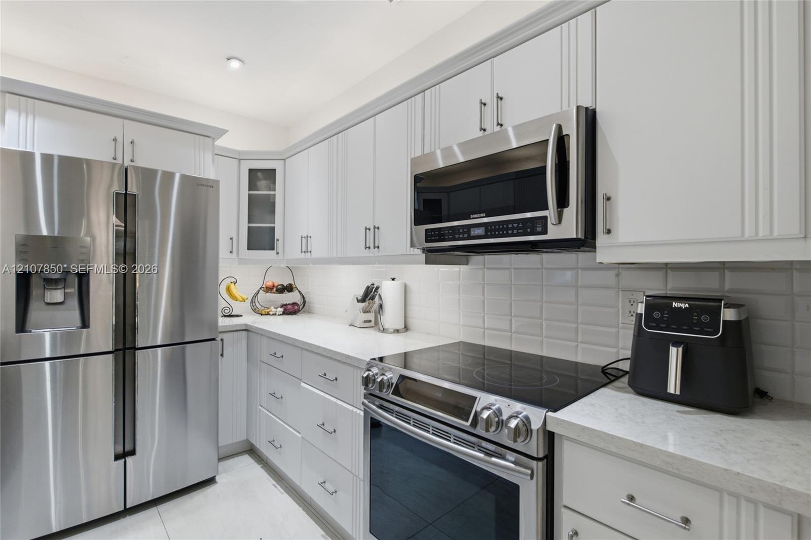 Kitchen featuring white shaker-style cabinetry, stainless steel appliances, white quartz countertops, and a subway tile backsplash