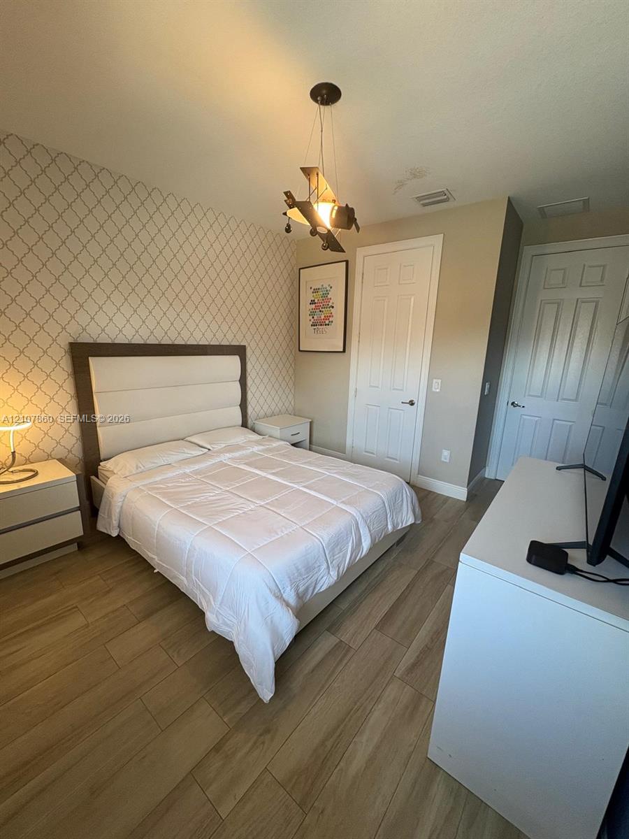 Wood-finish flooring, patterned accent wall, and multi-panel interior doors