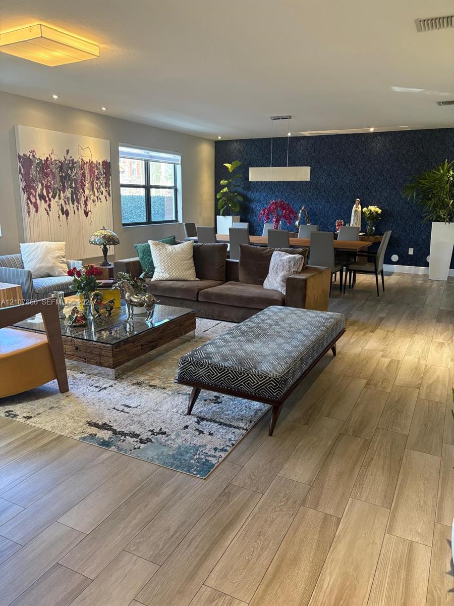 Wood-finish flooring throughout, navy blue accent wall, recessed lighting, and rectangular pendant light fixture