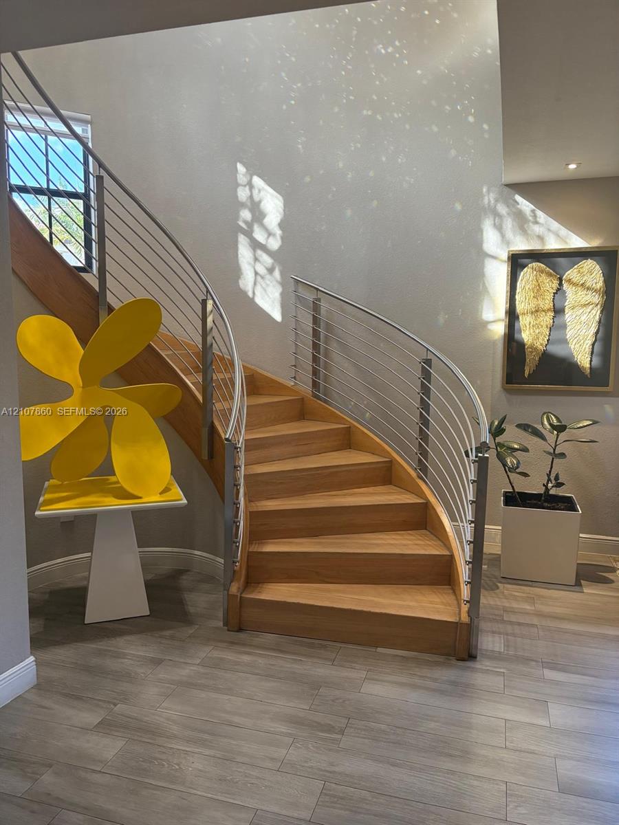 Curved staircase featuring wood treads and a stainless steel cable railing system