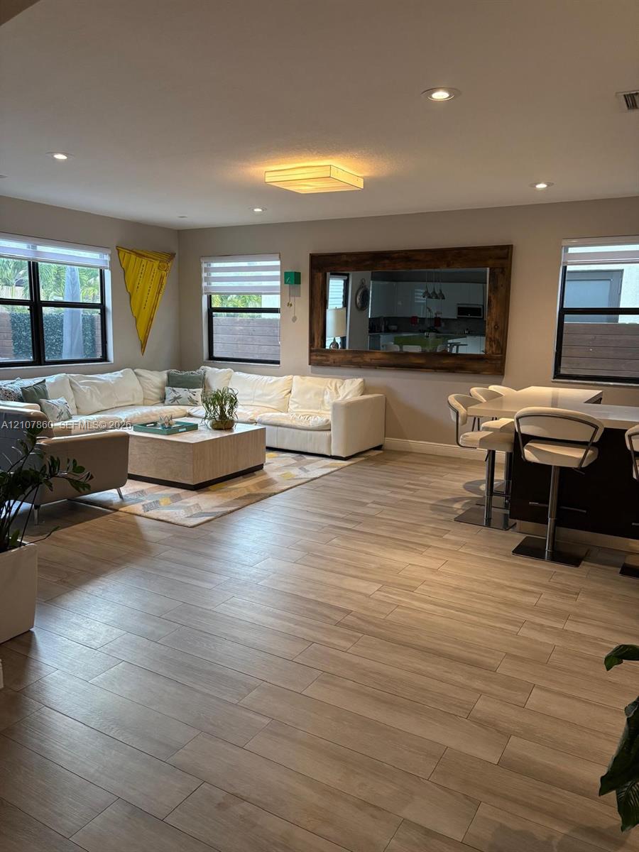 Open-concept interior featuring wood-finish tile flooring, recessed lighting, and a large wall-mounted mirror with a wood frame