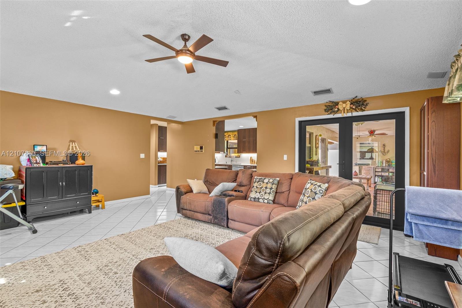 Living area featuring tile flooring, recessed lighting, a ceiling fan, and black-framed French doors