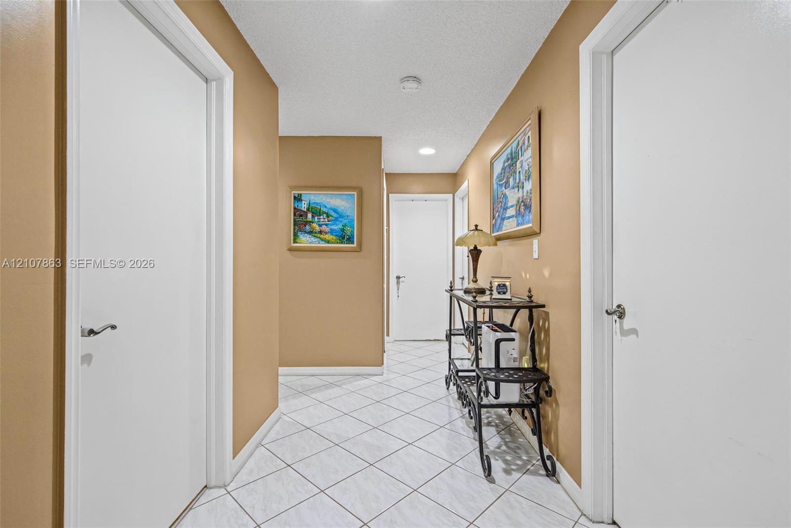 Hallway featuring white panel doors with lever-style hardware, recessed ceiling lighting, and diagonal-pattern tile flooring