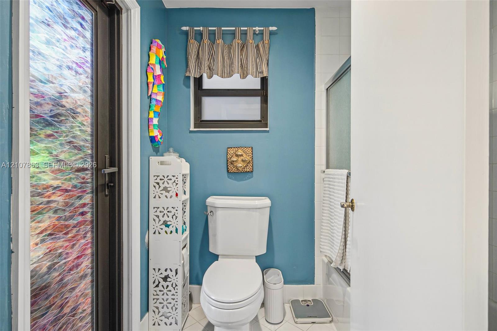 Bathroom featuring a decorative glass door panel, tiled flooring, and a framed window