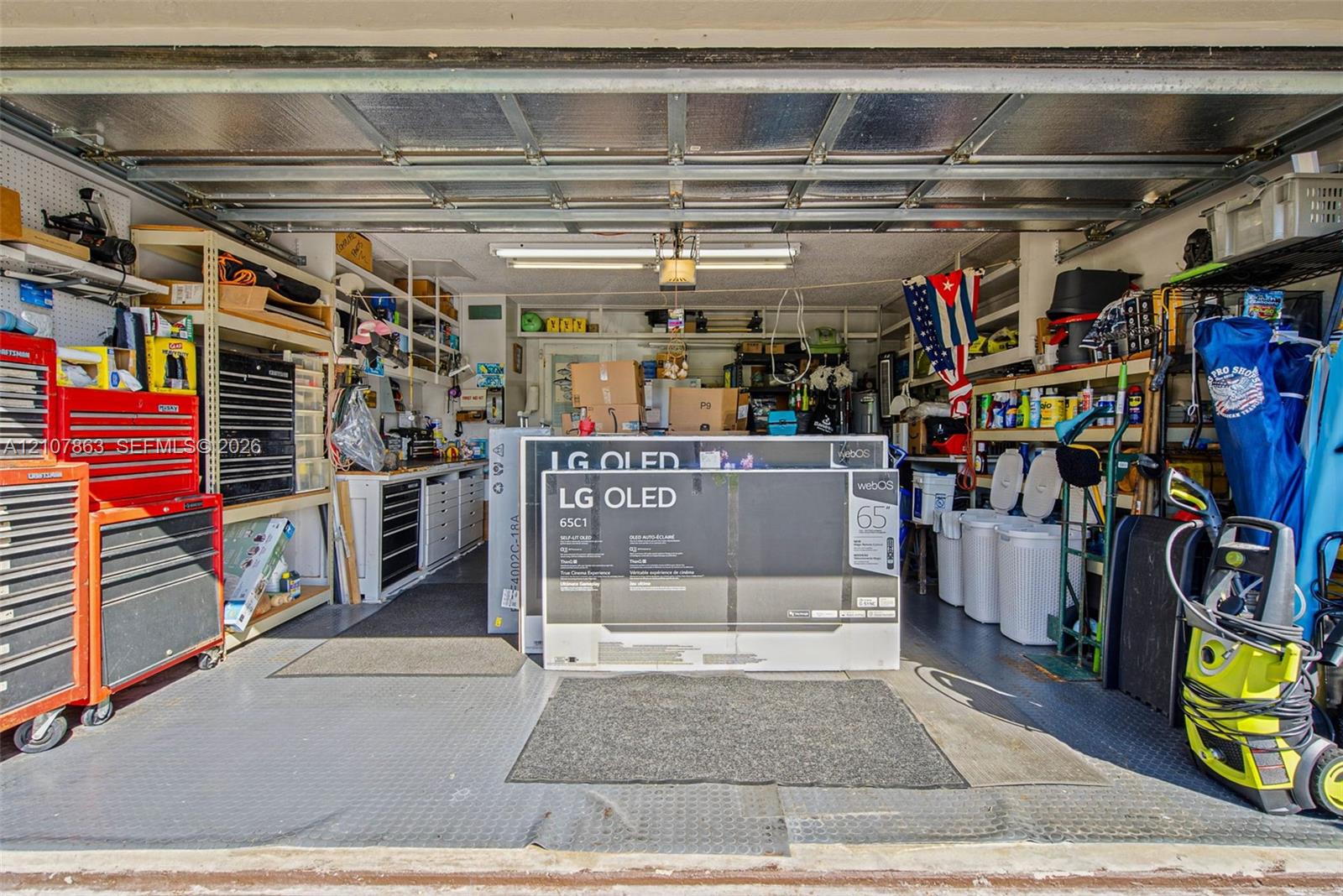 Garage space featuring built-in industrial shelving, integrated workbench cabinetry, textured floor matting, and overhead fluorescent lighting
