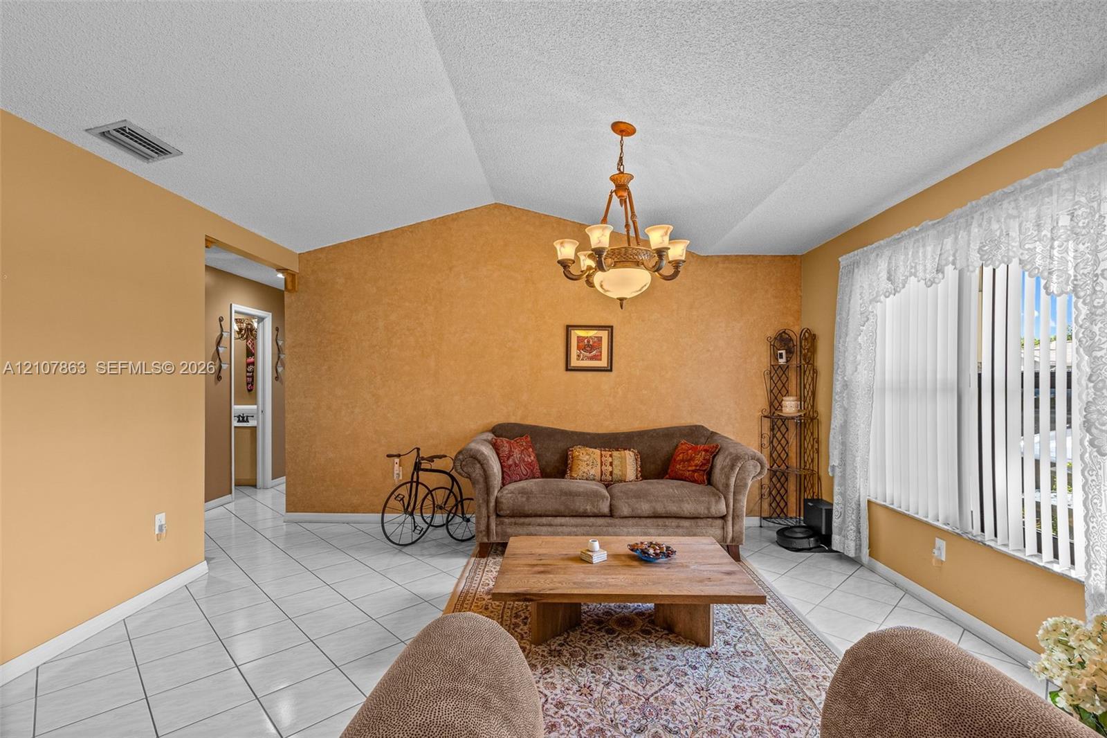 Vaulted ceilings featuring a central multi-arm chandelier and diagonal-set ceramic tile flooring