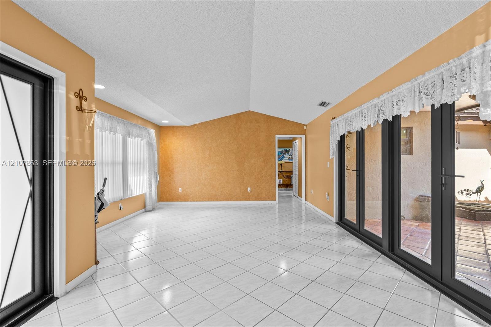 Vaulted ceilings, large-format tile flooring, multi-panel glass door systems, and recessed lighting