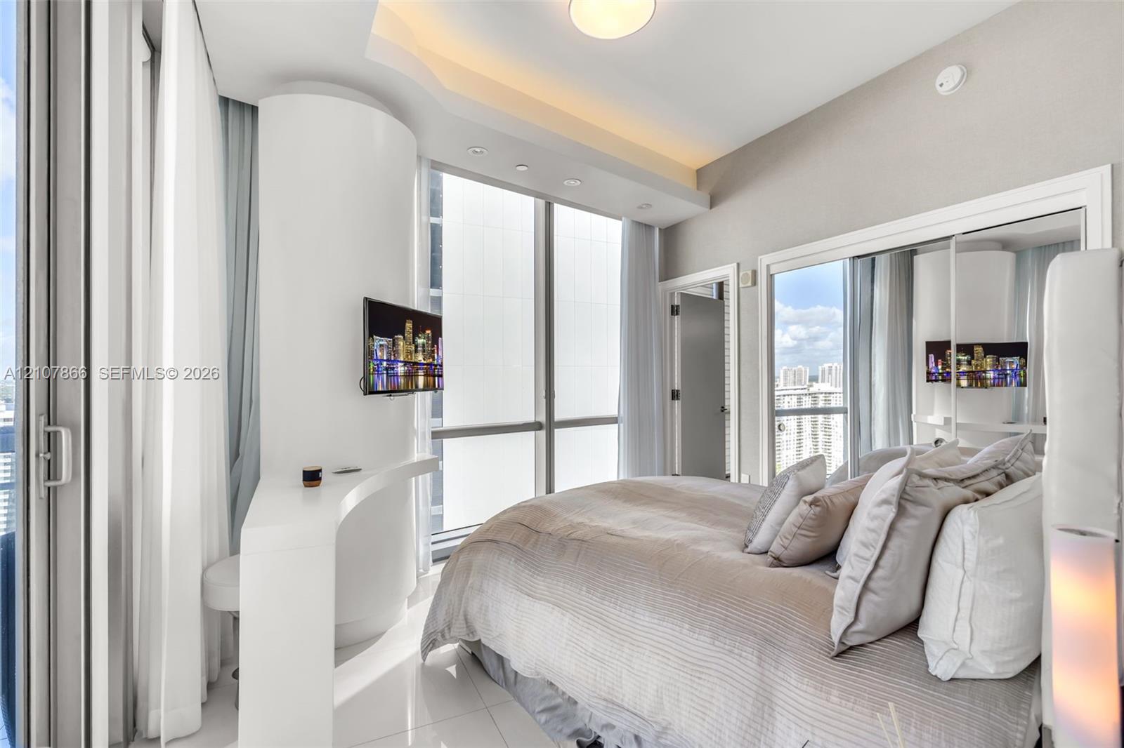 Floor-to-ceiling windows, built-in desk, recessed lighting, and mirrored closet doors