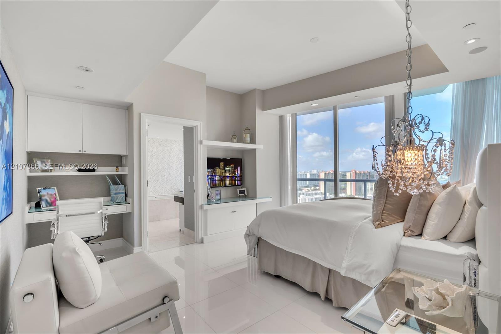 Floor-to-ceiling windows, built-in desk with overhead cabinetry, polished tile flooring, recessed lighting, and ornate crystal chandelier