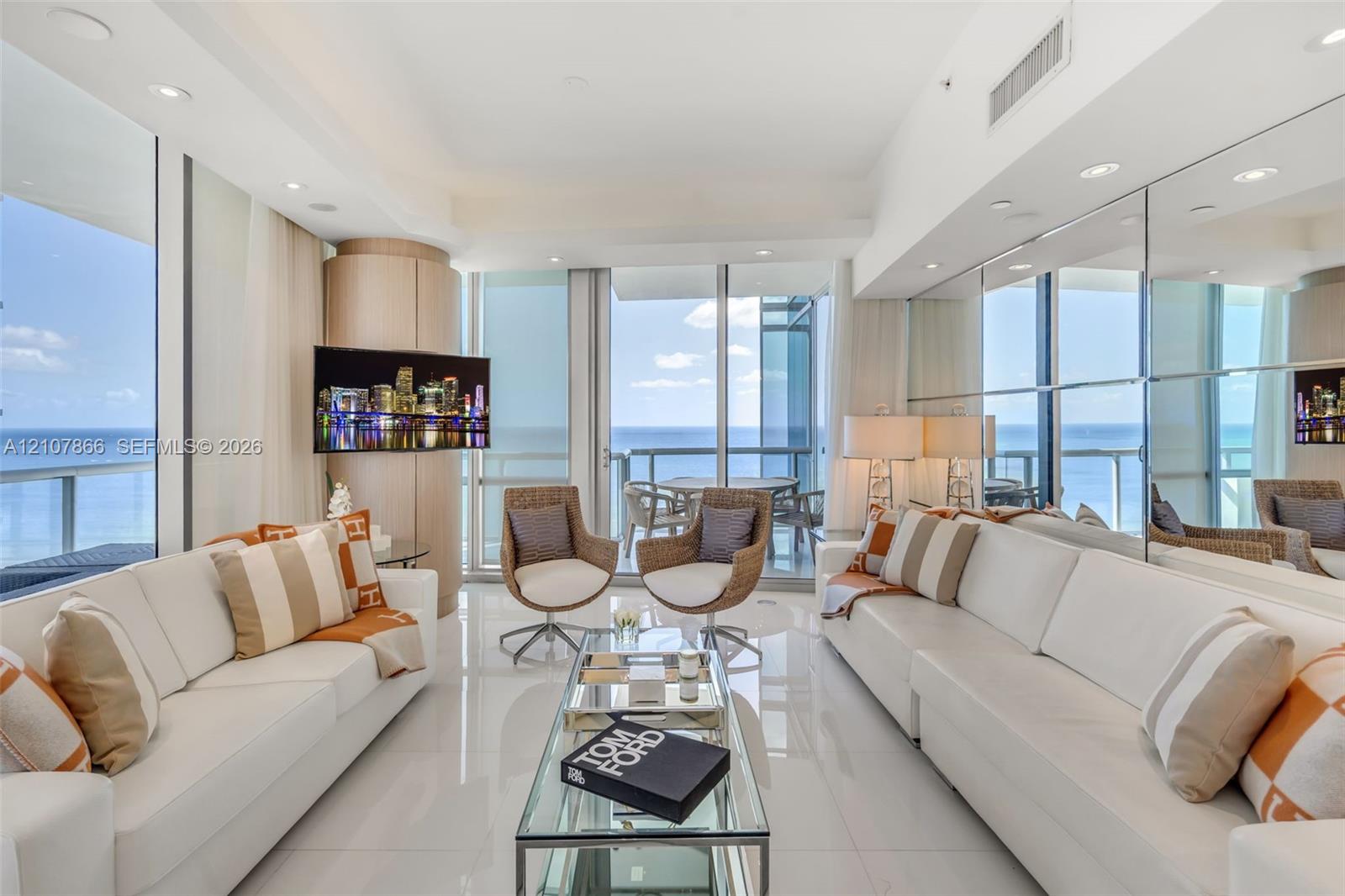Floor-to-ceiling glass walls, polished stone flooring, recessed lighting, mirrored wall accents, and a private balcony