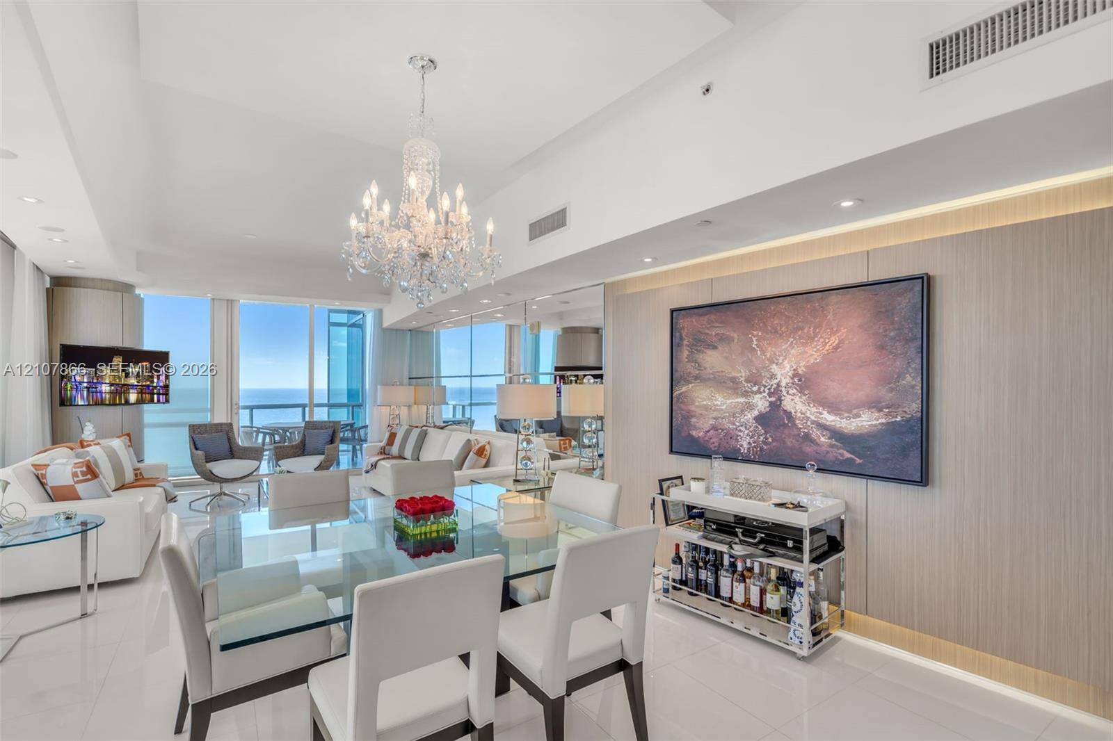 Expansive floor-to-ceiling glass windows, custom wood-paneled feature wall with integrated accent lighting, polished tile flooring, and decorative crystal chandelier