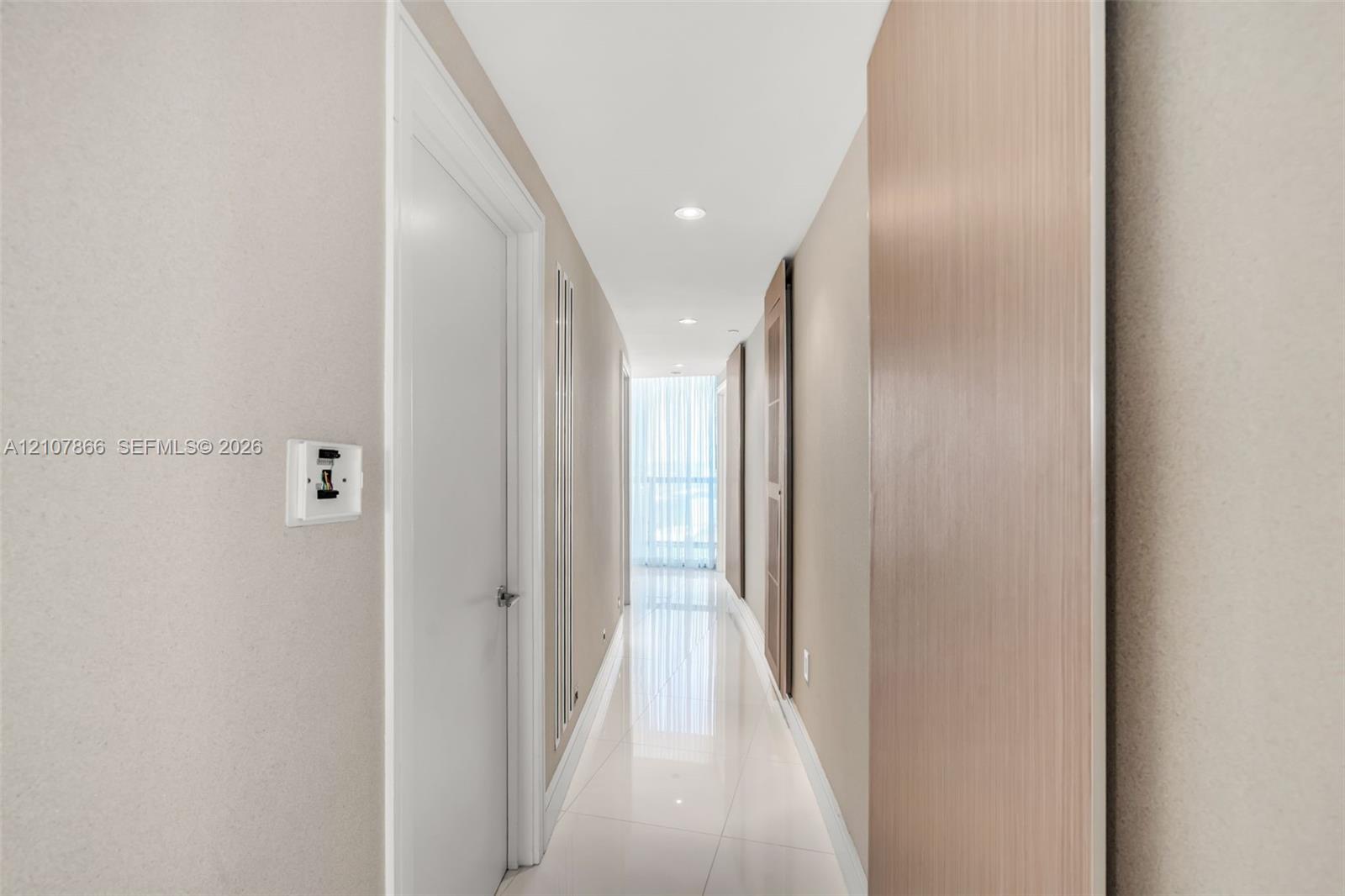 Hallway featuring large-format tile flooring, recessed lighting, and light wood-tone door finishes