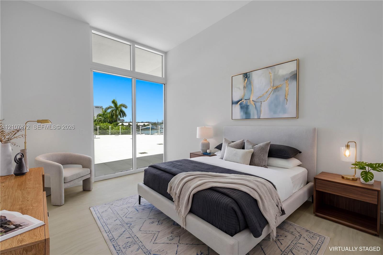 High-ceilinged room featuring wood-finish flooring, floor-to-ceiling glass paneling, and an expansive exterior terrace