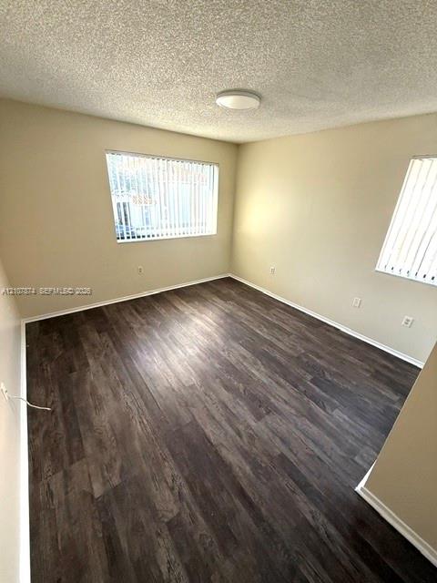 Room featuring wood-finish flooring, neutral wall paint, and dual windows with vertical blinds
