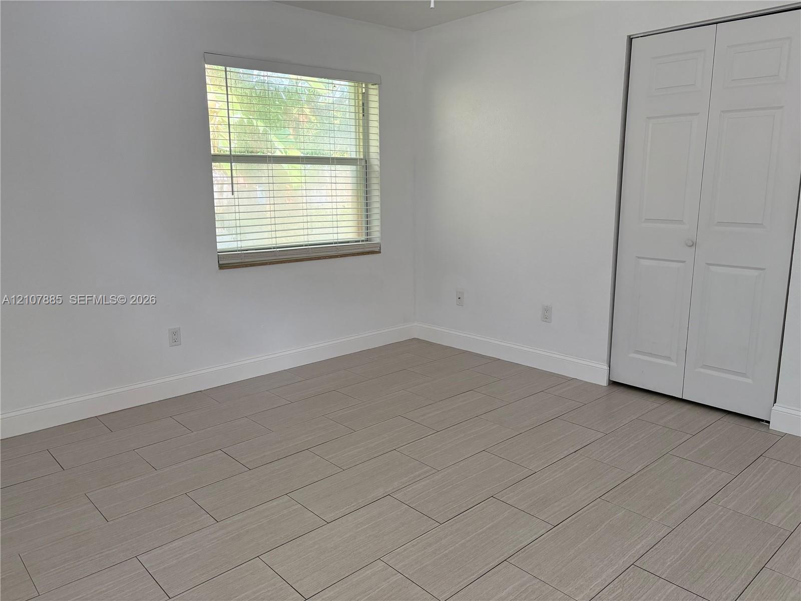 Neutral-toned tile flooring, light-filled interior, and dual-panel closet doors