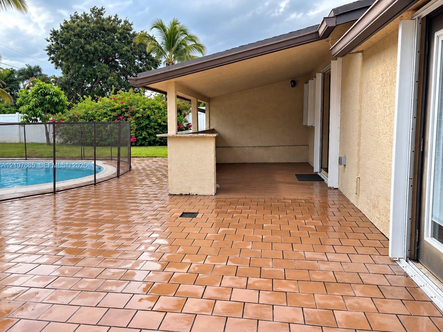 Covered patio featuring a built-in bar, tiled flooring, and a swimming pool with a protective mesh enclosure