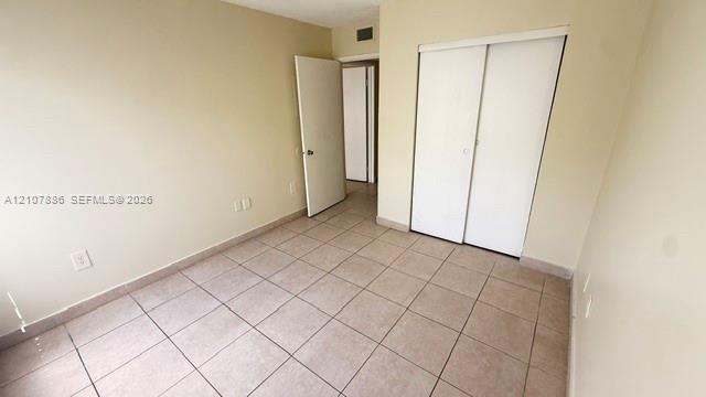Neutral-toned ceramic tile flooring, sliding closet doors, and solid-core interior doors